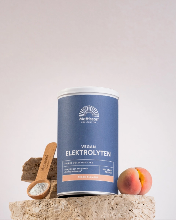 Mattisson Vegan electrolyten mockup met als synoniem Mattisson Elektrolytes mockup van pot in de peach flavor smaak op een steen met een perzik en een schepje met poeder